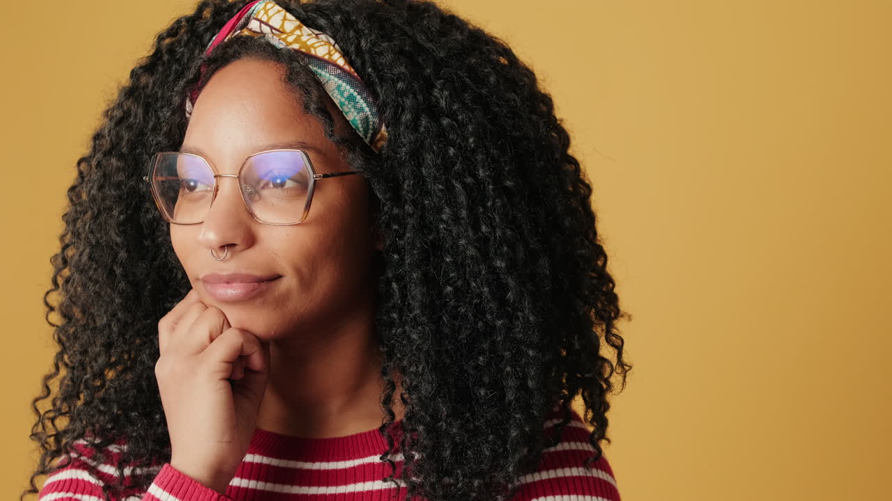 Thoughtful Young Woman with Curly Hair and Glasses Looking Away
