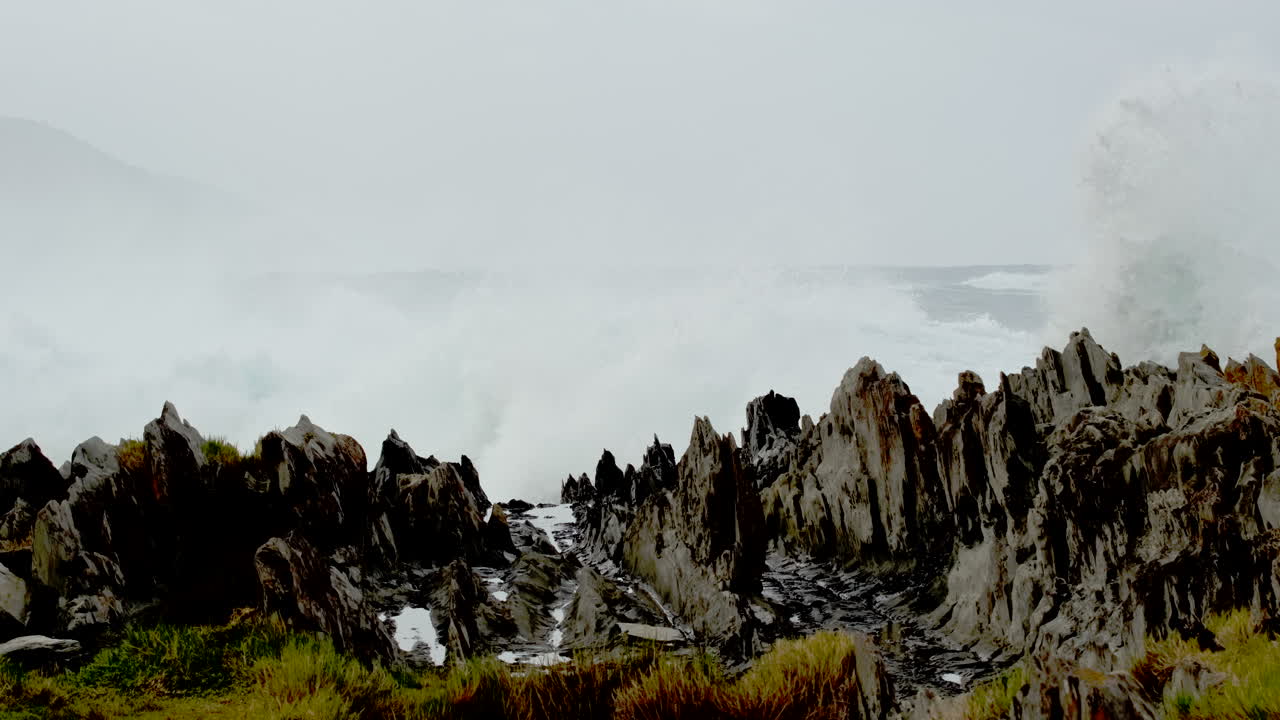 Strong waves smash into jagged rocky shore at Storms River mouth, slow motion