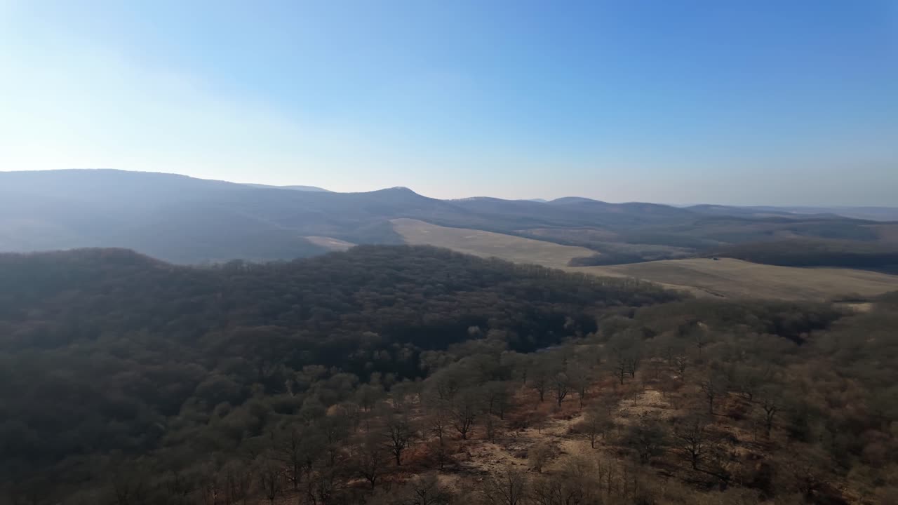 Breathtaking pan shot showcasing the rolling hills and vast landscapes surrounding Hollókő, Hungary.
