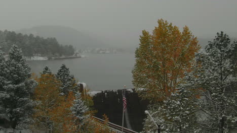 Downtown-Evergreen-Lake-dam-American-flag-Colorado-historic-downtown-aerial-drone-blizzard-fall-autumn-winter-first-snowfall-colorful-aspen-trees-Rocky-Mountain-front-range-Denver-light-slowly-motion