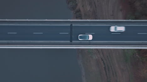 Vista-Aérea-A-Vista-De-Pájaro-Del-Camión-Eléctrico-Blanco-Que-Se-Mueve-En-La-Carretera-Del-Puente,-Rastreando-El-Tiro-Del-Dron