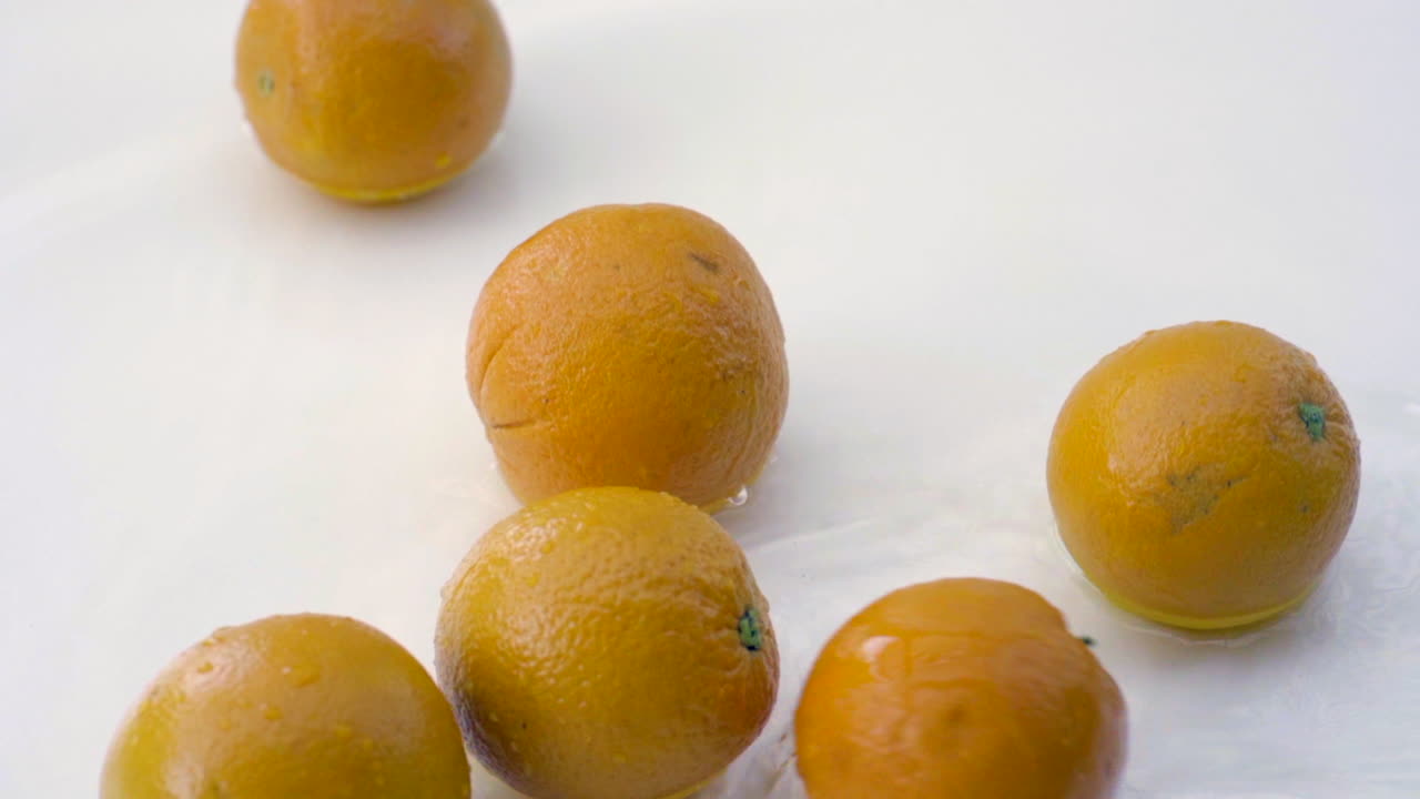 slomo de naranjas en agua sobre fondo blanco