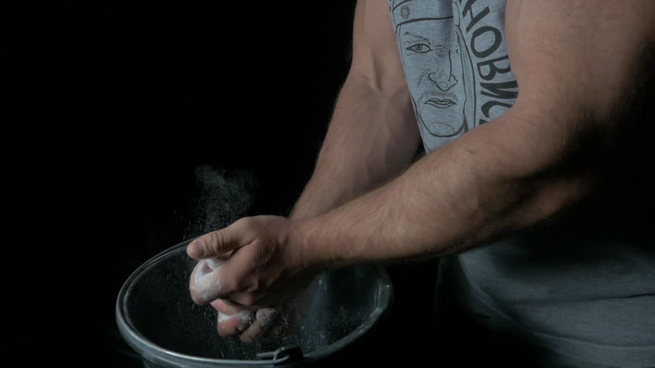 Atleta de força se preparando para o treino, aplicando giz nas mãos