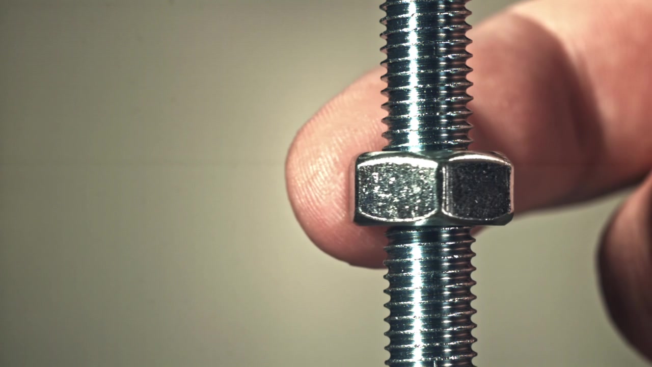 Close-up de uma Porca Sendo Rosqueada em um Parafuso de Metal