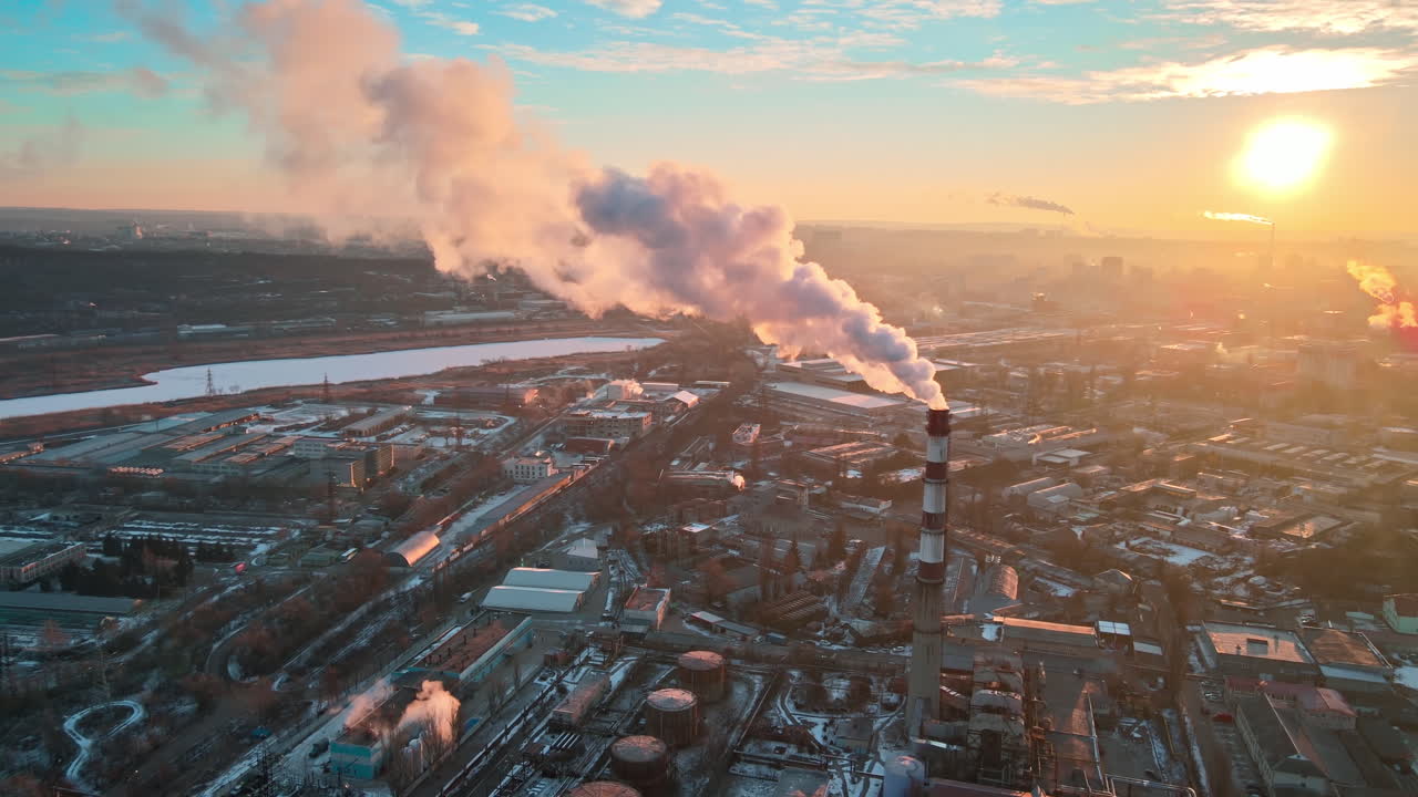Aerial drone view of Chisinau at sunrise. Thermal station with smoke coming out of the tube. Buildings, roads and bare trees. Good weather, snow on the ground. Moldova