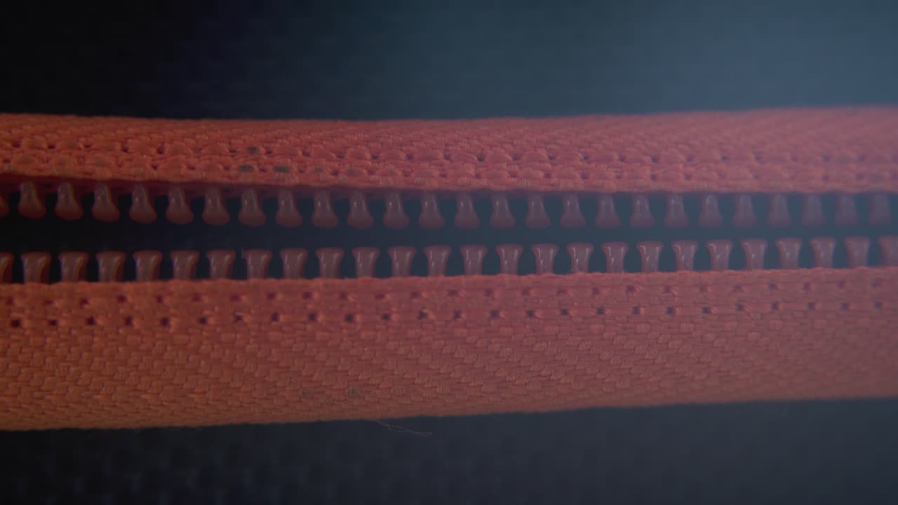 하드 케이스 지퍼가 닫히는 시네마틱 매크로 클로즈업, 오렌지색 레크처, 금속 지퍼, 블랙 박스, 사진 장비, 전문 스튜디오 조명, 정적 4k 비디오