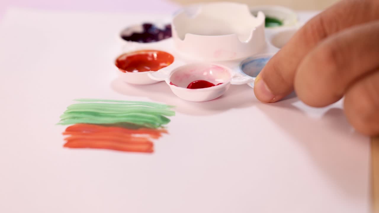 Artist hand mixes watercolor paints on palette, close-up, soft lighting, shallow depth of field