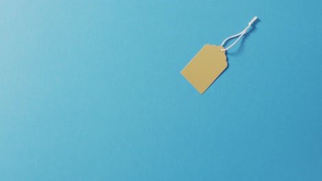 yellow sale tag and string on blue background with copy space