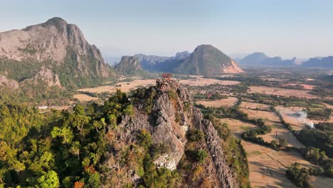 drone orbit of jagged karst peaks above nam song river valley near vang vieng, laos, showing phou pha dang ridge and surrounding limestone mountains in golden evening light