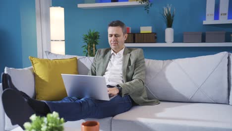 Relaxing-mature-man-resting-on-sofa-at-home-using-laptop,-typing-on-keyboard.