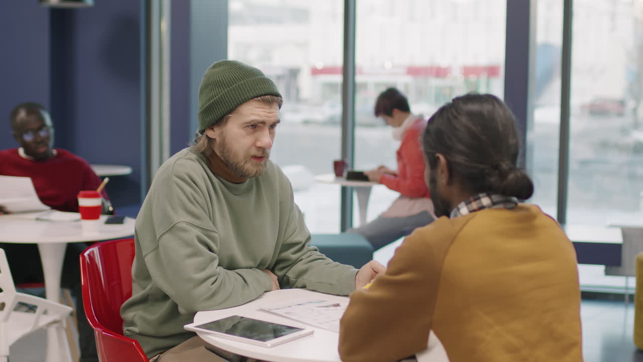 Male Colleagues Discussing Work in Office Cafeteria