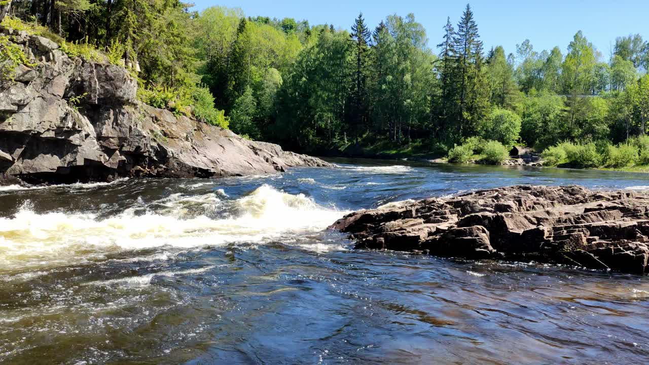 A large amount of water flowing in the Numedalslagen river in Norway on a sunny day