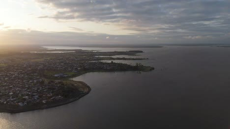 Aerial view of a coastal town at dusk with serene waters and a striking horizon. The scene blends urban and natural elements, creating a tranquil landscape of Federacion, Entre Ríos, Argentina