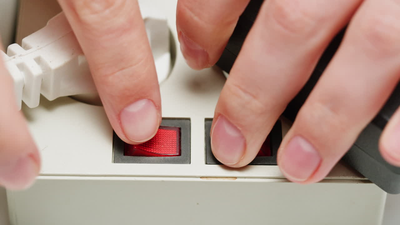 White power strip with many various of cords and cables in close-up. An extension cord with many power sockets. Adapter with phone, headphones, usb connectors.Tangled wires on table. Trying to untangle many messy cables.