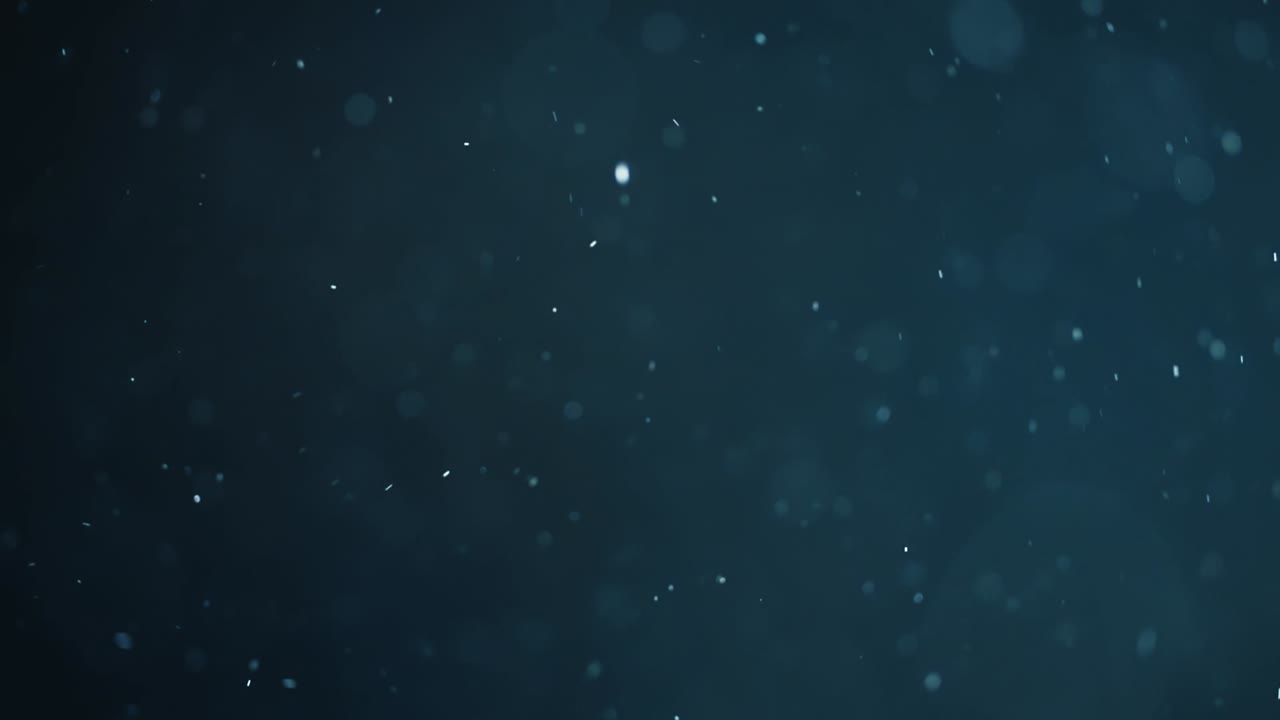 Svævende abstrakt partikel-bokeh på mørk baggrund.