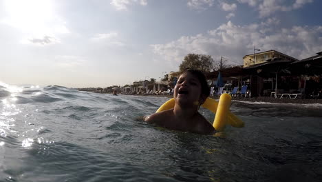 Footage-of-Caucasian-boy-having-fun-with-waves-at-Kalamata-beach,-Greece