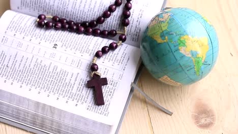 praying-to-God-with-cross-on-bible-on-table-with-globe-no-people-stock-video