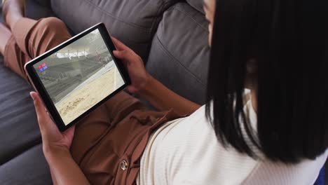 composite of woman sitting at home on couch watching athletics long jump event on tablet