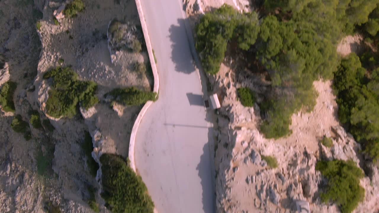 아름다운 공중 풍경은 마요르카의 울창한 초록색으로 둘러싸인 휘어지는 도로를 보여주는 칼라 라자다의 매혹적인 풍경을 포착합니다.