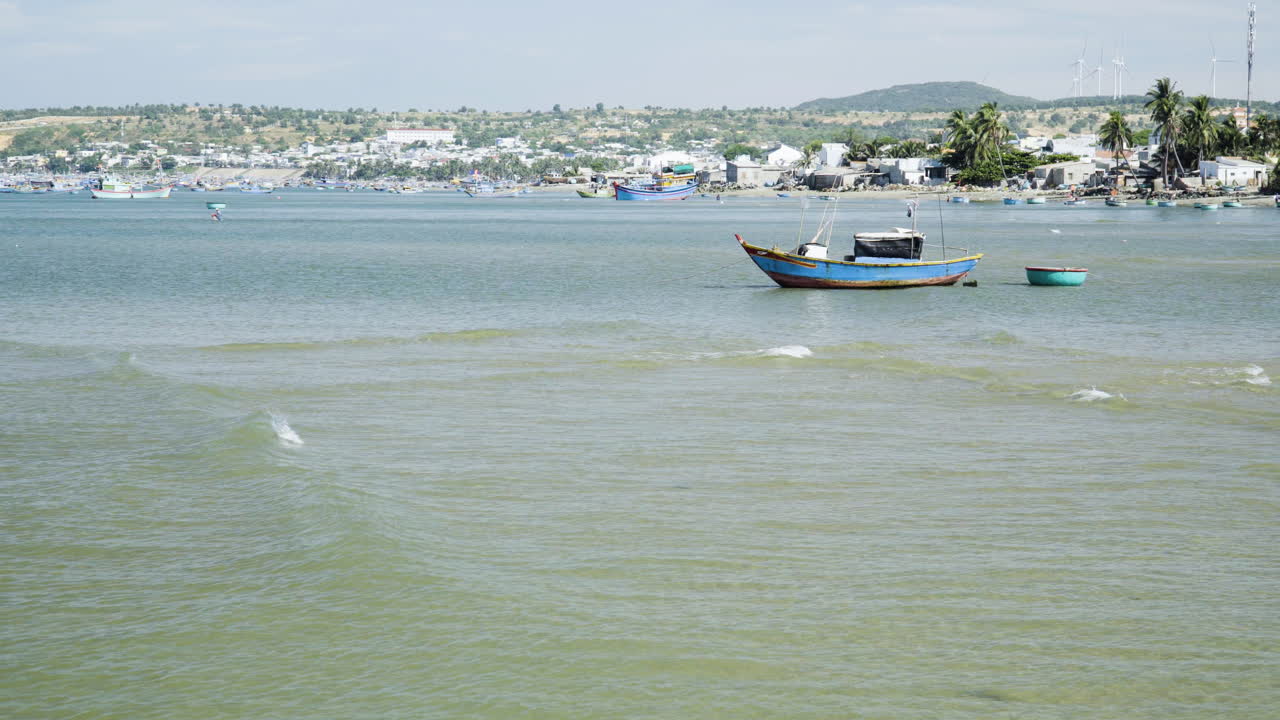barco de pesca vietnamita flotando en la costa del puerto oceánico mientras las olas tranquilas llegan