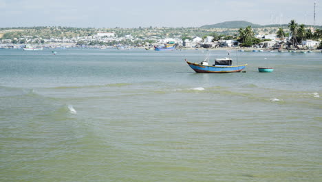 Vietnamese-fishing-boat-floating-in-ocean-harbor-coastline-as-calm-waves-roll-in