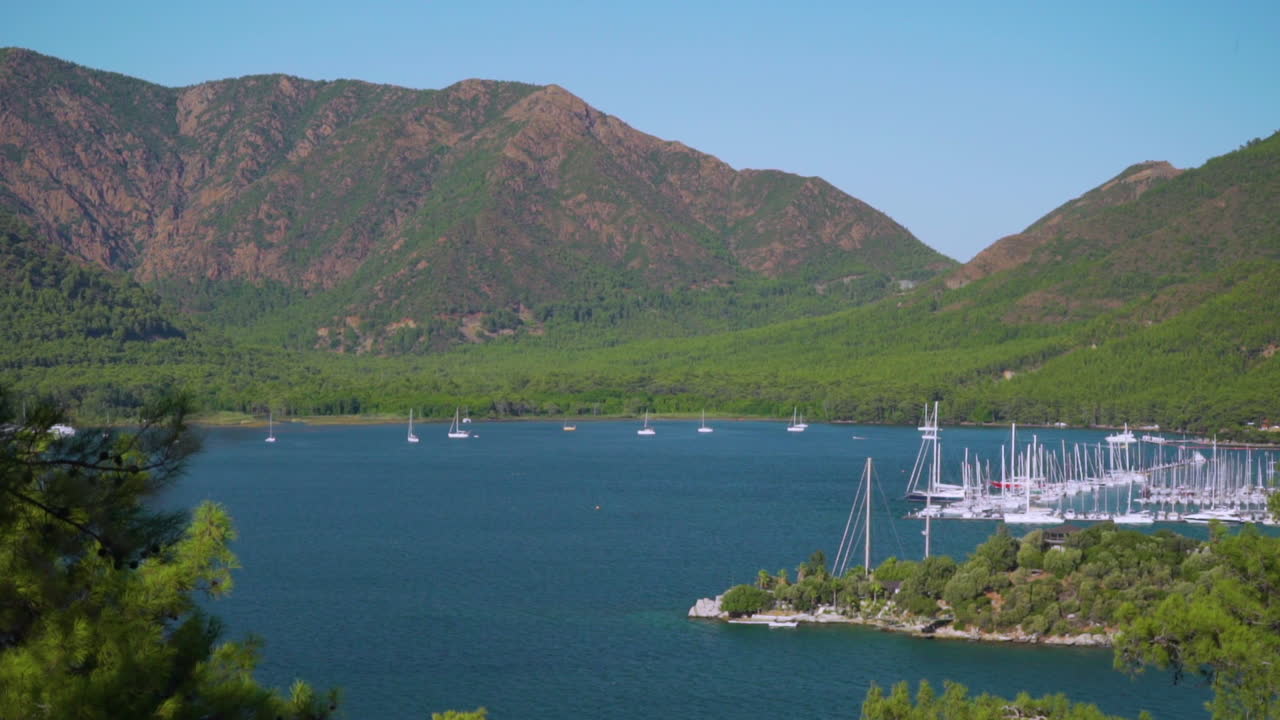 This shot depicts a panoramic view by of Marmaris harbour with a backdrop to pine-clad mountains.