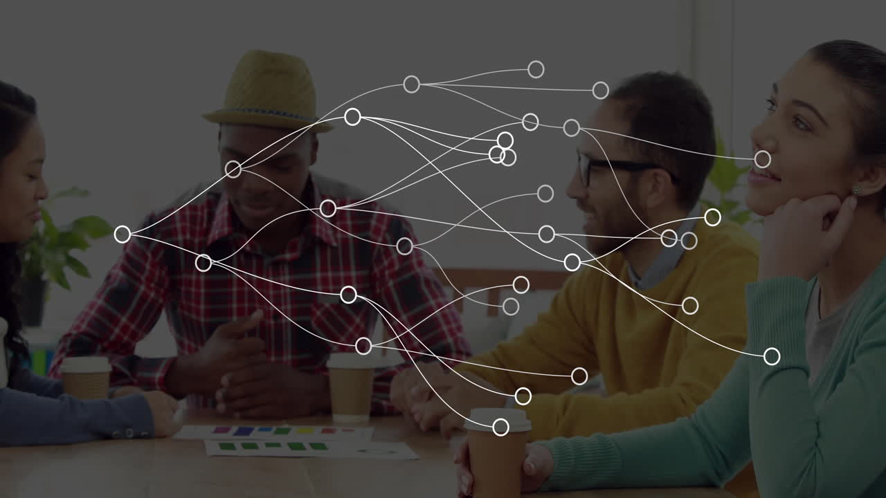 Graphic designers leaning around table in studio, reviewing color swatches with floating charts