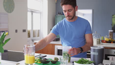 hombre haciendo una bebida de jugo saludable con ingredientes frescos en un exprimidor eléctrico después del ejercicio