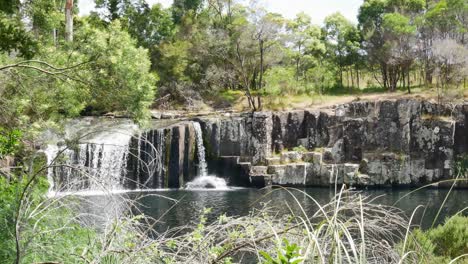 panning shot of idyllic kerikeri waterfall during sunny day in national park in new zealand