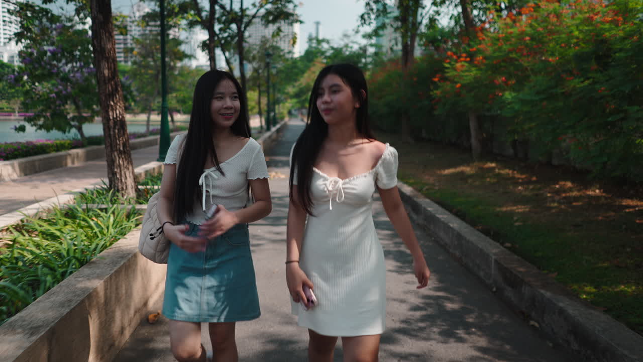 หญิงสาวเอเชียสองคนเดินเล่นและพูดคุยกันในสวน