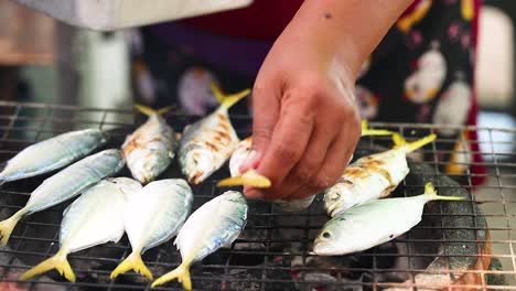 hands preparing mackerel on a grill