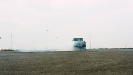 Toma-En-Cámara-Lenta-De-Un-Todoterreno-Grande-Haciendo-Donuts-En-Un-Campo-De-Carreras-Creando-Una-Nube-De-Humo