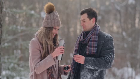 a caring man warms his wife's hands in the winter on the street in a snow-covered park