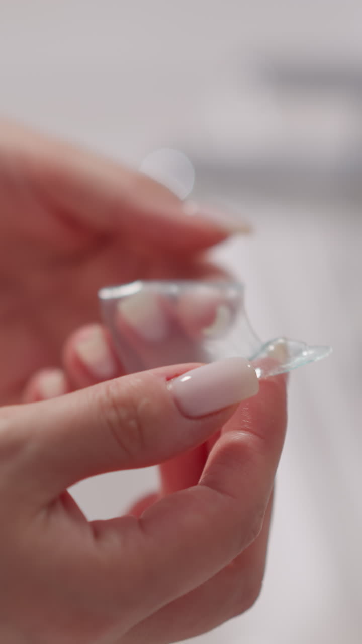 la mano de la mujer sostiene un parche transparente para la piel alrededor de los ojos. la dama con manicura toma parches cosméticos hidratantes para los ojos en las manos en la ducha en cámara lenta