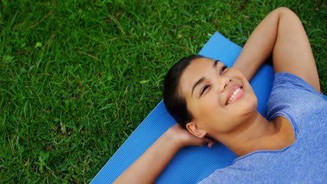 Beautiful-woman-lying-on-exercise-mat-in-garden-4k