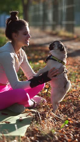 woman and her pug dog enjoying an autumn park walk