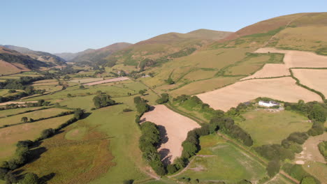 aerial drone shot moving across farmland in a welsh valley surrounded by mountains