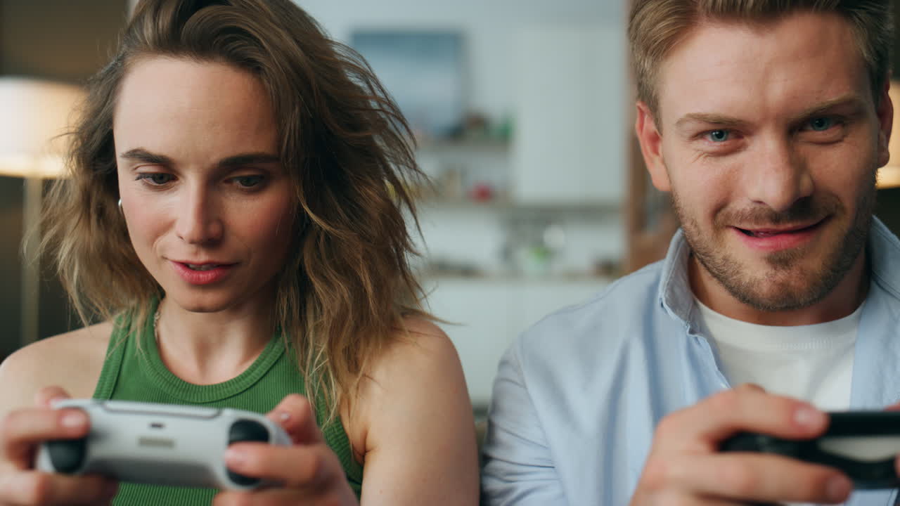 Excited gamers playing joysticks home closeup. Flurried couple holding gamepads