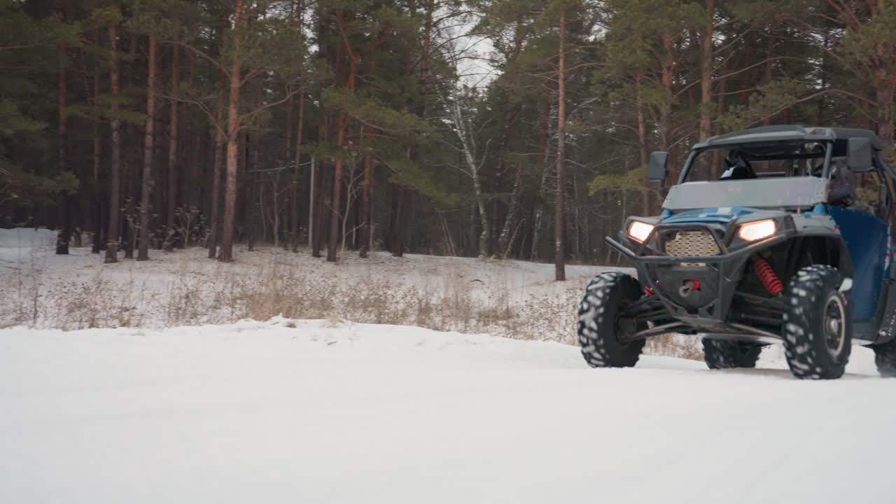 ATV nella neve. Un veicolo a motore sfreccia attraverso un boschetto di pini innevato con alberi alti. Un veicolo fuoristrada si muove costantemente attraverso una pineta invernale con nevicata e alberi imponenti.