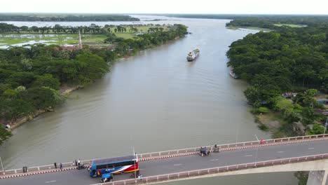 aerial flying over gabkhan bridge in jhalokati, bangladesh with traffic going past and boat seen in distance