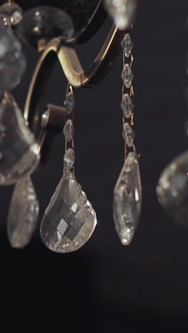 shiny transparent drop shaped crystal ornate on vintage chandelier in semi-dark room closeup. home decor classic element. design ideas for interior