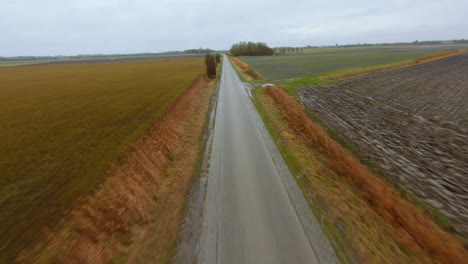 Fast-aerial-shot-following-a-road-in-a-rural-are-surrounded-by-farms