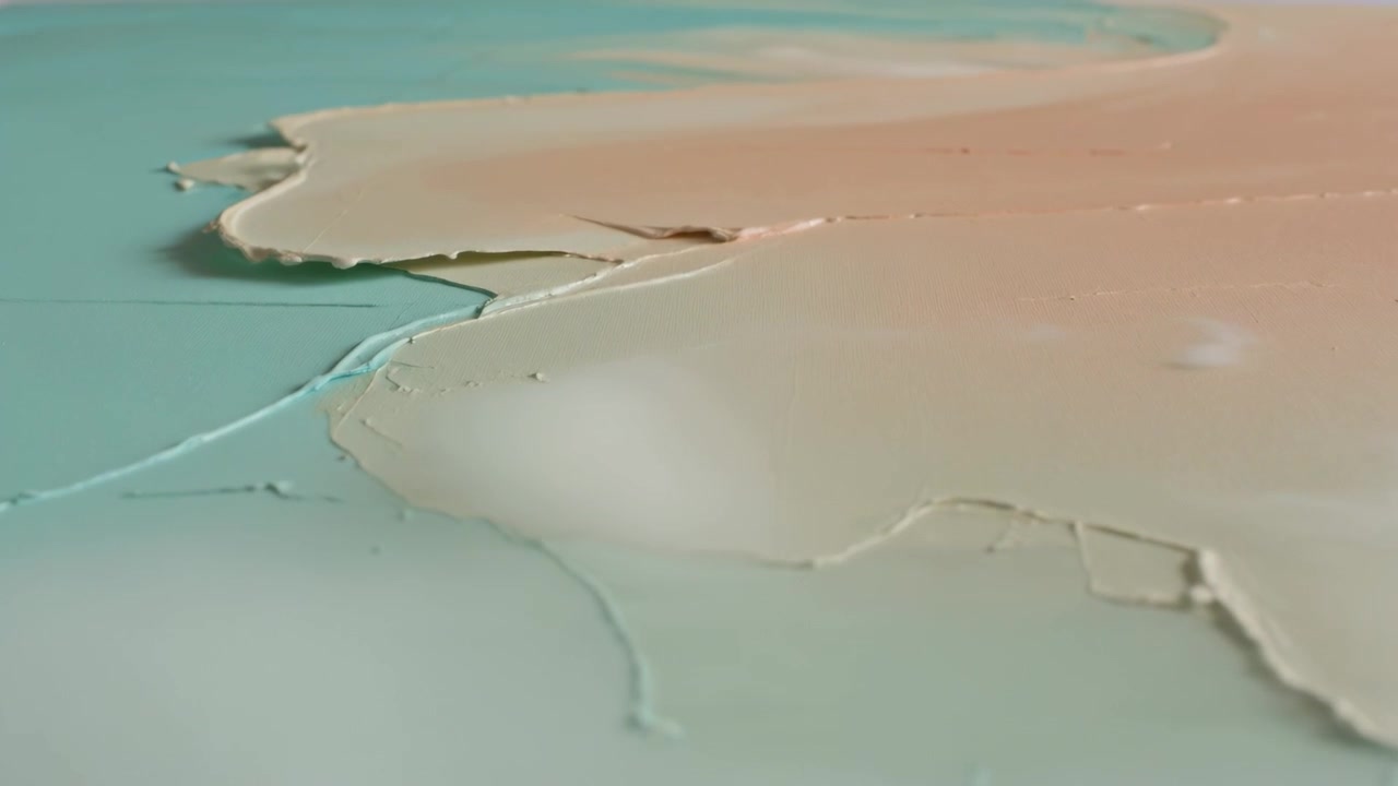 Pulling camera revealing peach-beige over teal paint smear at studio tabletop, exposing torn edges