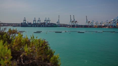 Experience-the-magic-of-a-captivating-timelapse-view-of-a-harbor-featuring-cranes-against-the-backdrop-of-a-breathtaking-emerald-green-sea-in-kalafrana,-Malta