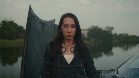 woman by a broken-down car by a lake