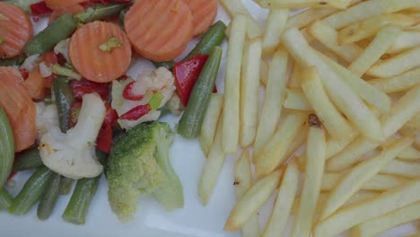 plates featuring french fries served with stir-fried meat and assorted vegetables