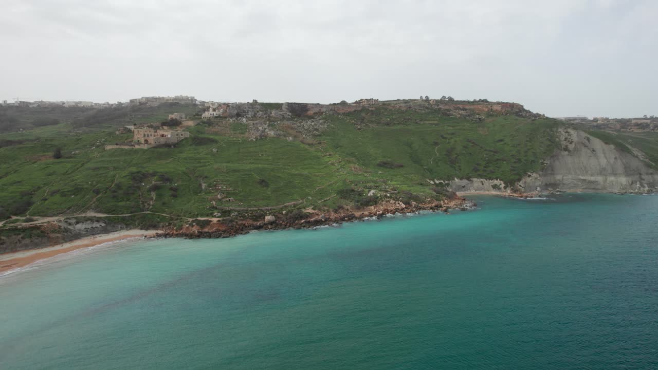 playa tropical en la base de una montaña con agua turquesa en malta, isla de gozo