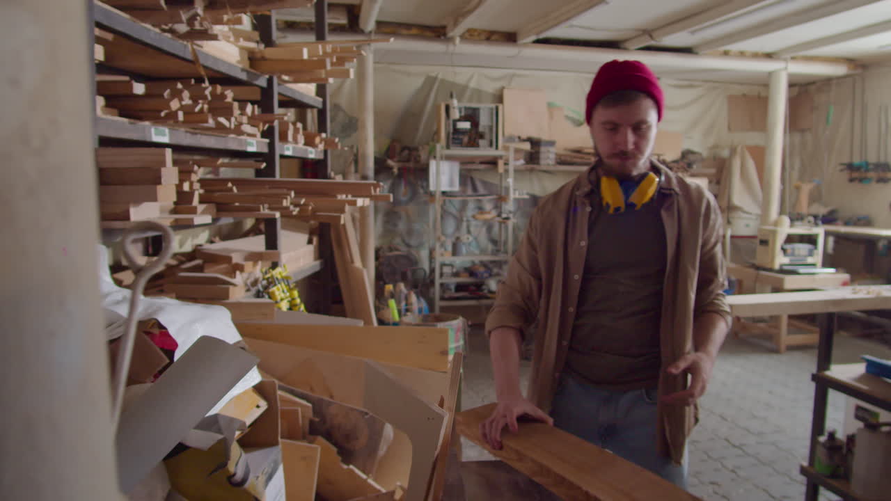 Carpenter Taking Wooden Plank for Work and Putting Safety Earmuffs