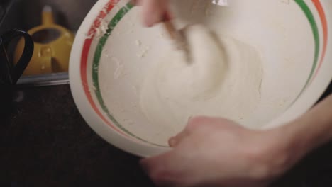 manual method of mixing dough in a bowl using a wooden spoon - closeup shot