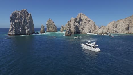 aerial shot of a yacht arriving to the arch of los cabos, baja california sur